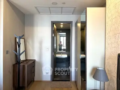 Modern bedroom with stylish furniture and a glimpse of a sleek bathroom.