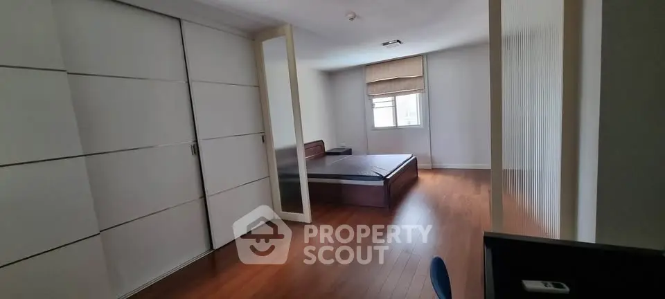 Spacious bedroom with wooden flooring and large wardrobe