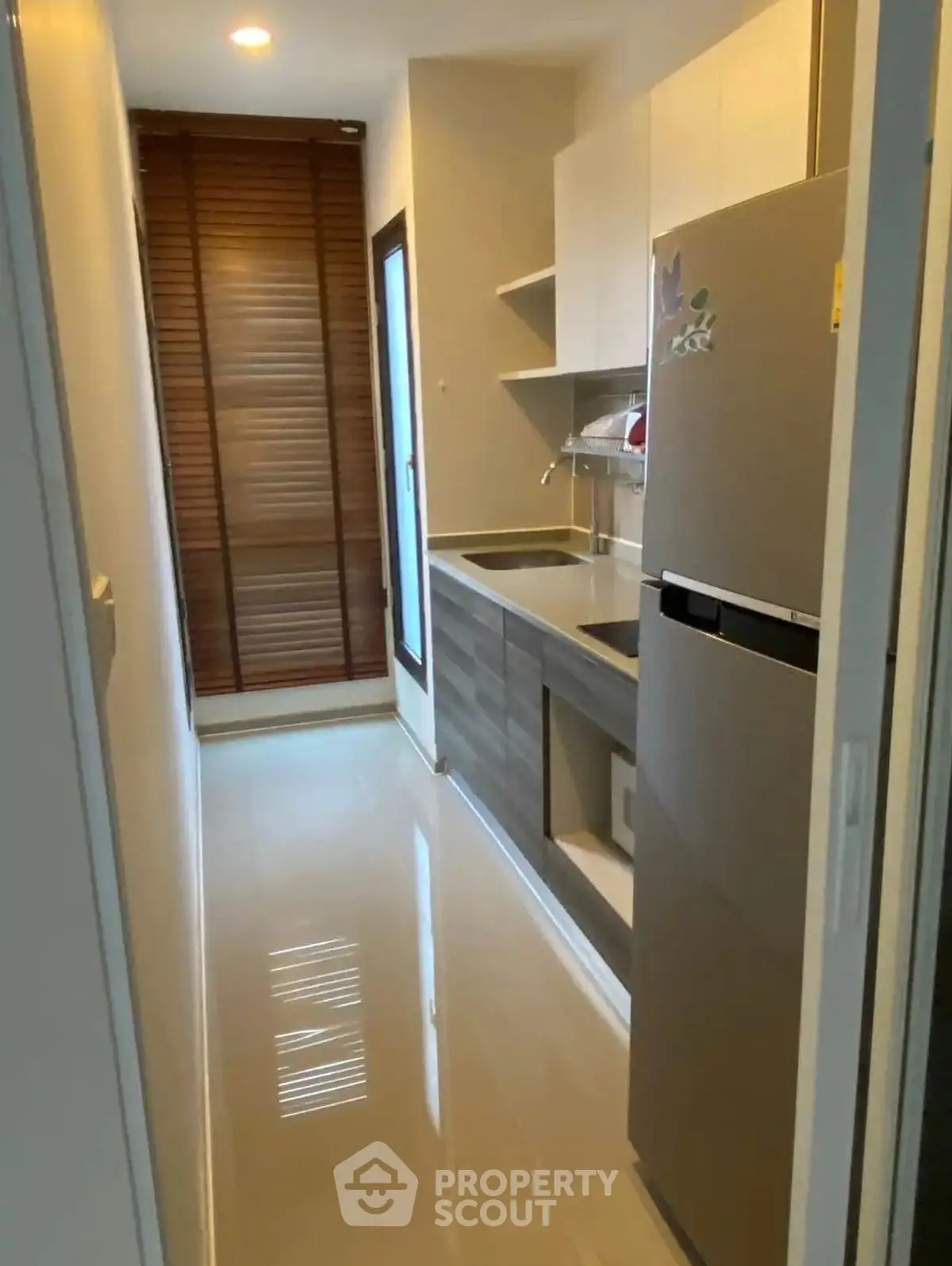 Modern compact kitchen with sleek cabinets and stainless steel fridge in a cozy apartment.