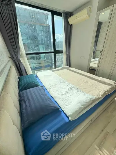 Modern bedroom with large window and city view, featuring stylish decor and air conditioning.