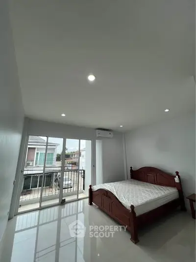 Spacious bedroom with balcony access and natural light in modern apartment.