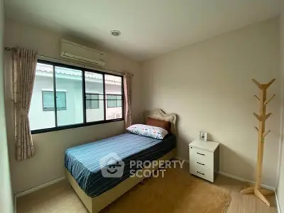 Cozy bedroom with single bed, air conditioning, and natural light from large window.