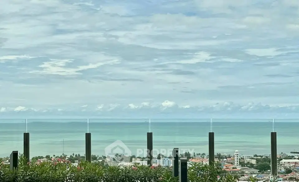 Stunning ocean view from a high-rise balcony with glass railing.
