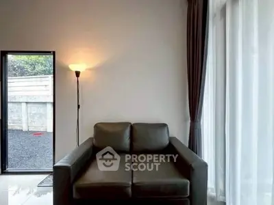 Cozy living room corner with modern leather sofa and floor lamp by large window.