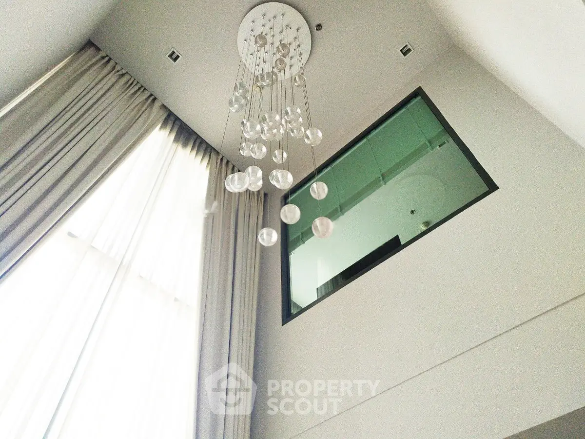 Elegant high ceiling living room with modern chandelier and large window