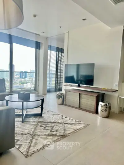 Modern living room with large windows and city view, featuring stylish furniture and decor.