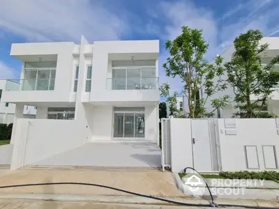 Modern white duplex with glass balconies and lush greenery