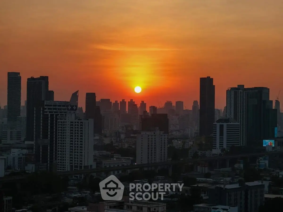 Stunning city skyline at sunset with high-rise buildings and vibrant orange sky.
