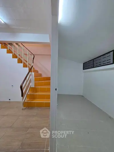 Spacious interior with modern staircase and ample natural light, perfect for versatile use.