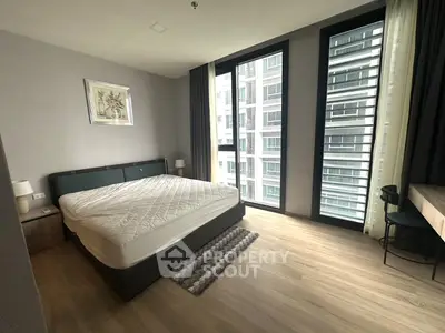 Spacious modern bedroom with large windows and stylish decor in urban apartment