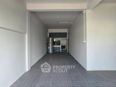 Spacious garage or storage area with tiled flooring and clean white walls.