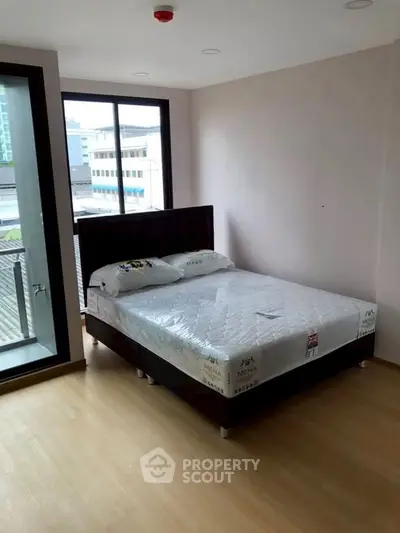 Spacious bedroom with large window and modern bed in urban apartment
