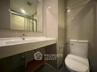 Modern bathroom with sleek fixtures and large mirror in a contemporary apartment.