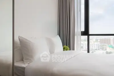 Modern bedroom with large window offering city view, featuring crisp white bedding and elegant curtains.