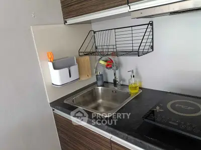 Modern kitchen with sleek countertop, induction stove, and stylish sink area.