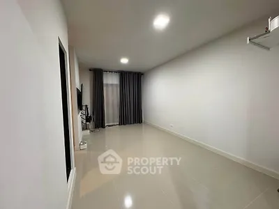 Spacious minimalist living room with sleek tile flooring and modern lighting, perfect for contemporary living.