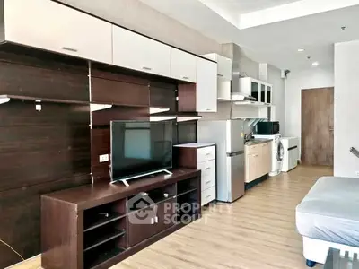 Modern studio apartment with sleek kitchen and entertainment unit, featuring wood flooring and ample storage.