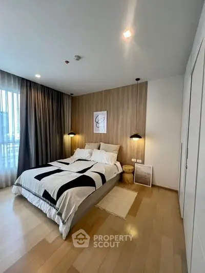 Modern bedroom with stylish decor and ample natural light, featuring a cozy bed and elegant lighting.
