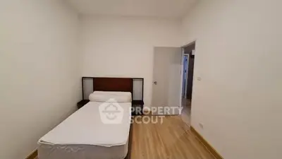 Minimalist bedroom with single bed and wooden flooring in modern apartment.
