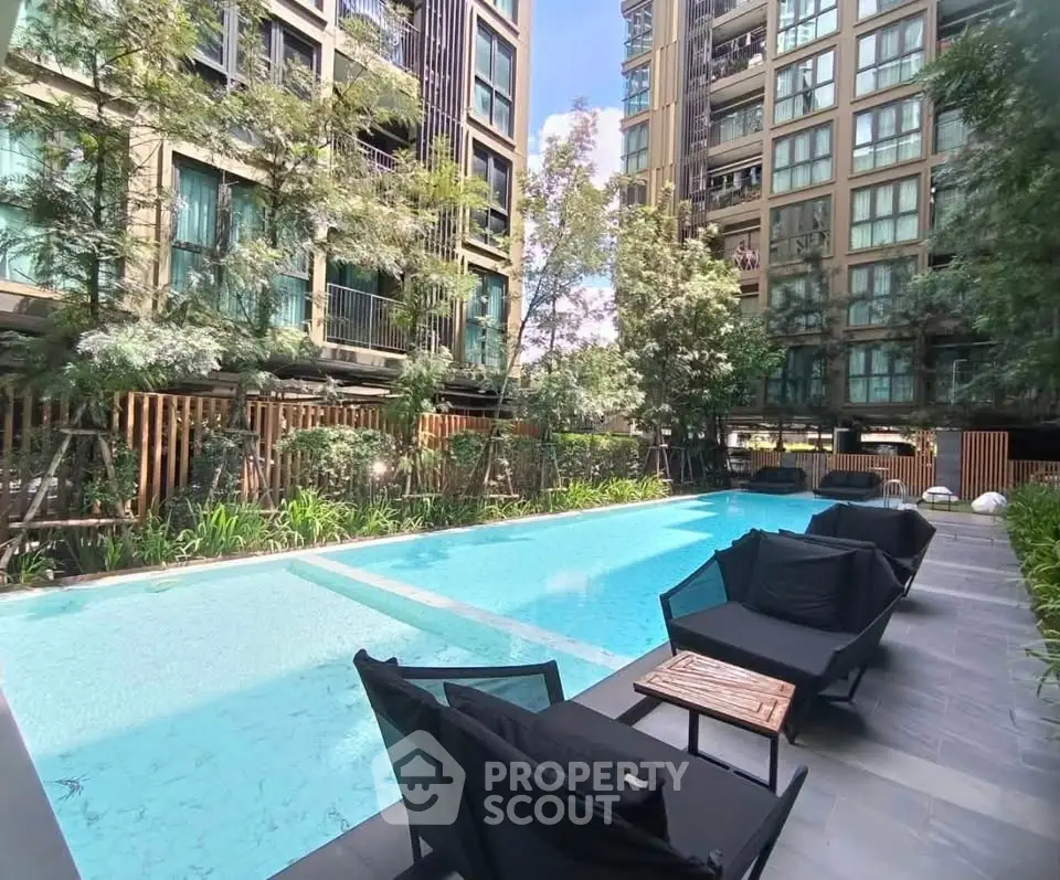 Luxurious apartment complex with a stunning outdoor pool and modern seating area.