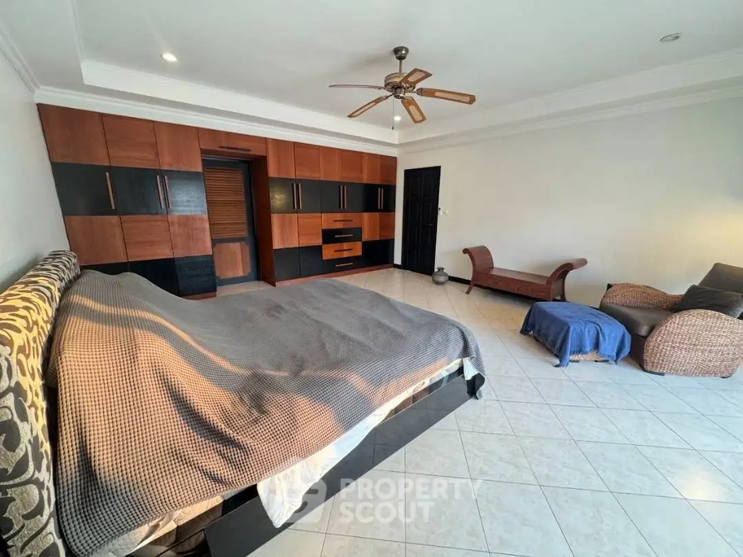 Spacious bedroom with modern wooden wardrobe and cozy seating area.