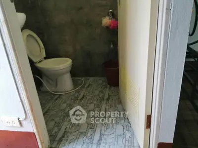 Compact bathroom with modern tile flooring and open door view.
