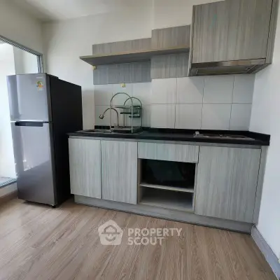 Modern kitchen with sleek cabinetry and stainless steel fridge in a bright apartment.