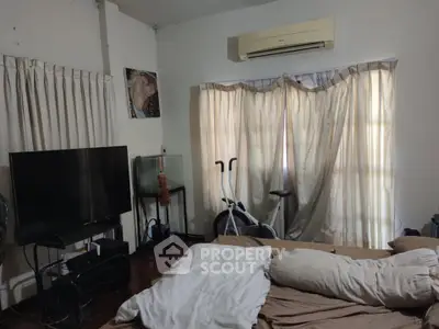 Cozy bedroom with air conditioning, TV, and exercise bike, ideal for relaxation and fitness.