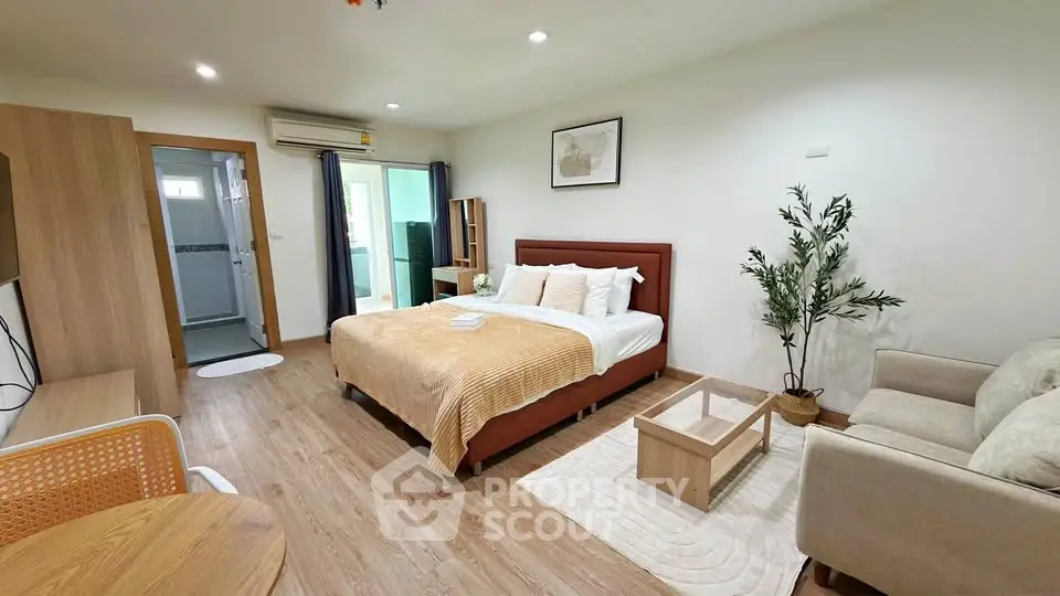 Spacious bedroom with modern decor and cozy seating area in a stylish apartment.