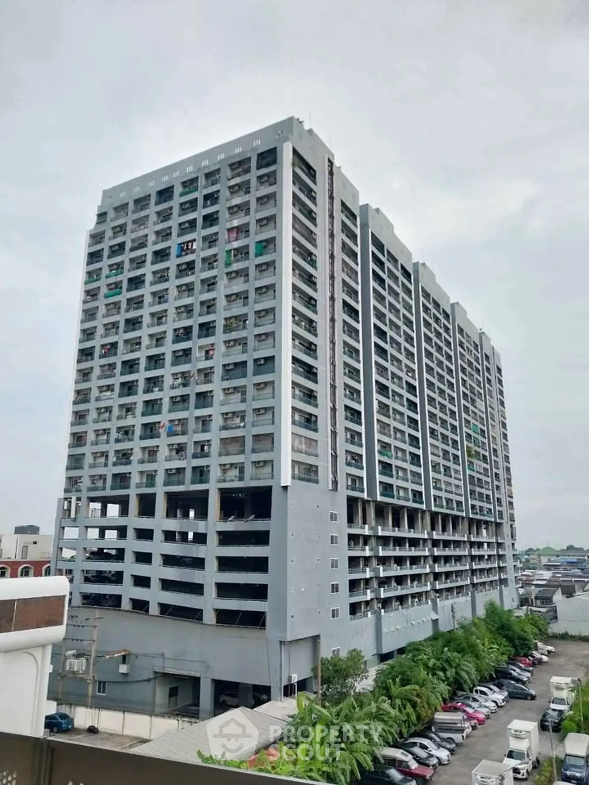 Modern high-rise residential building with ample parking and urban surroundings.