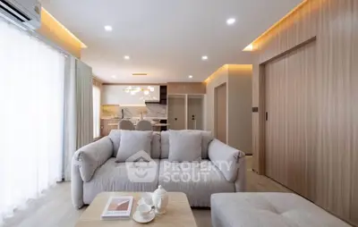 Modern living room with cozy sofa and open kitchen layout in stylish apartment.