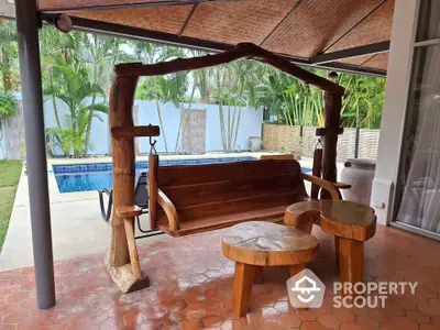 Charming patio with rustic wooden furniture and pool view, perfect for relaxation.