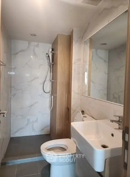 Modern bathroom with sleek fixtures and marble tiles, featuring a spacious shower area.