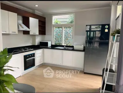 Modern kitchen with sleek appliances and open layout, featuring a gas stove and large refrigerator.