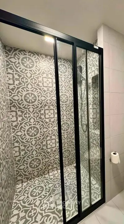 Stylish bathroom with patterned tiles and modern glass shower enclosure.