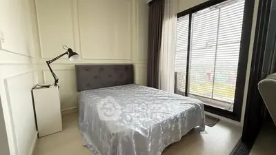 Modern bedroom with elegant decor and large window offering natural light