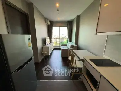 Modern apartment with open kitchen and cozy living area, featuring sleek appliances and a bright window view.