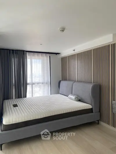 Modern bedroom with stylish bed and floor-to-ceiling windows for natural light.