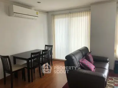 Cozy living room with dining area, featuring modern furniture and natural light from large windows.
