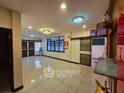 Spacious living room with tiled flooring and ample natural light, perfect for family gatherings.