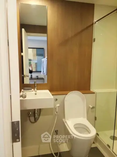 Modern bathroom with sleek design, featuring glass shower and compact sink.