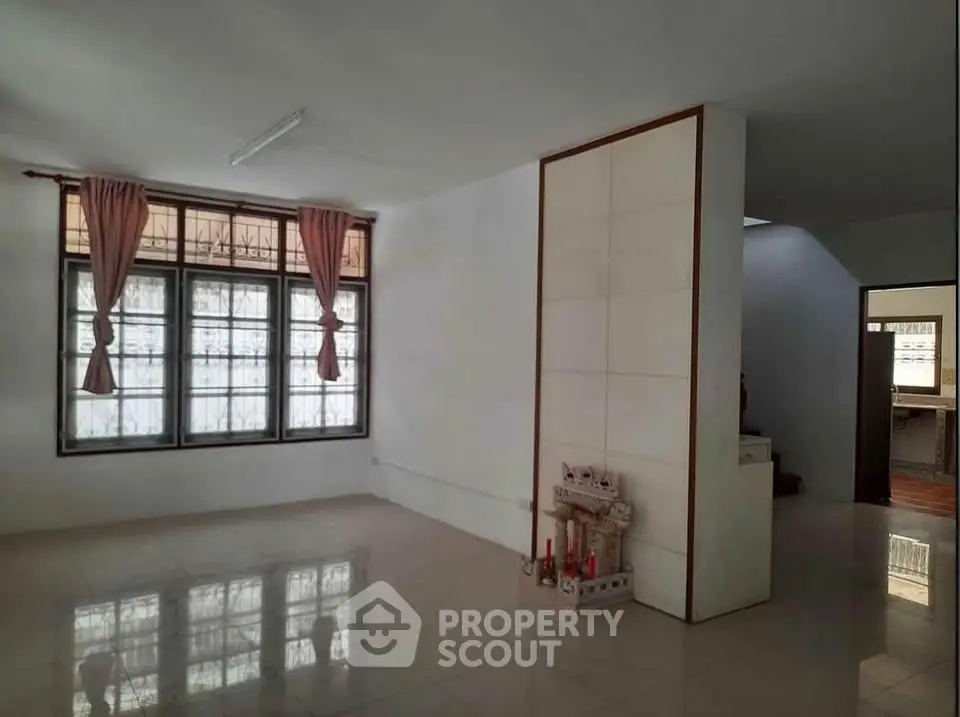 Spacious living room with large windows and tiled flooring, perfect for natural light and modern living.