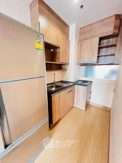 Modern kitchen with sleek wooden cabinets and stainless steel appliances in a compact layout.