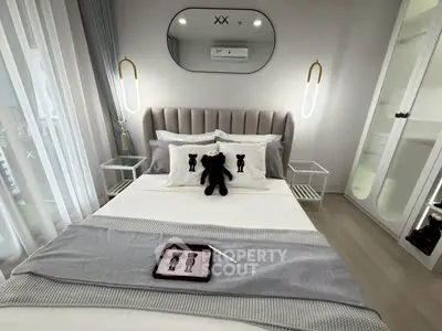 Modern bedroom with stylish decor and tablet on bed, featuring elegant lighting and plush bedding.