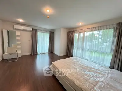 Spacious bedroom with large windows and modern furnishings in a bright, airy setting.