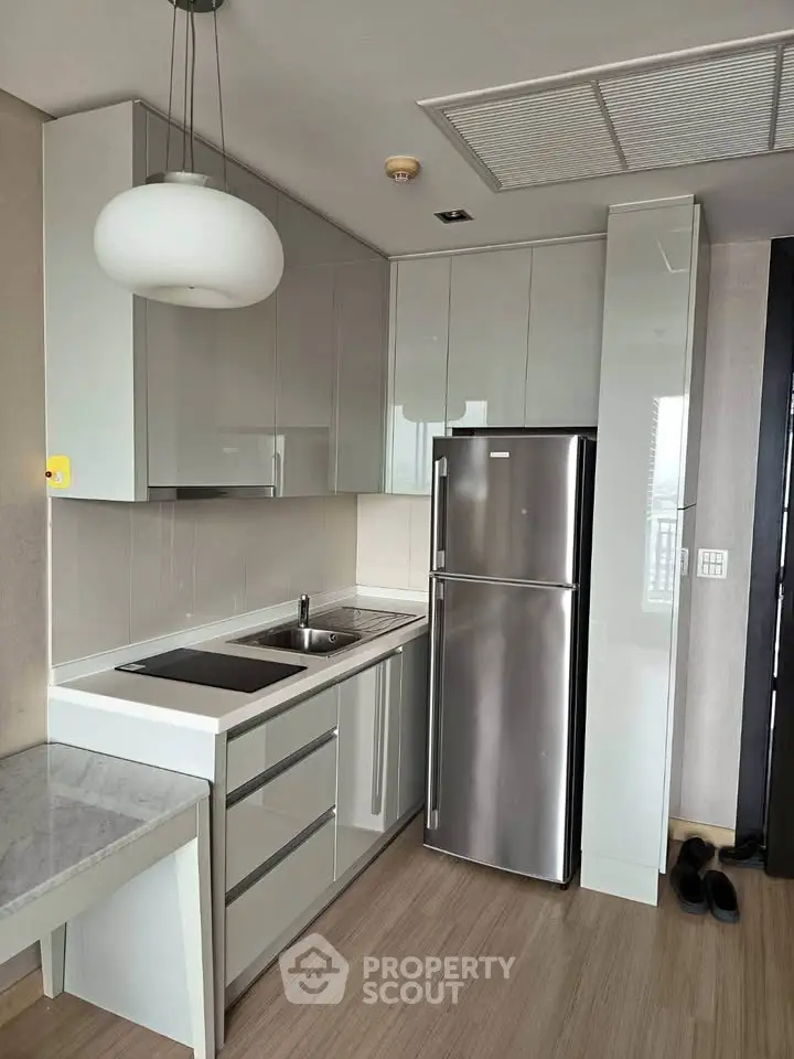 Modern kitchen with sleek cabinetry and stainless steel fridge in a stylish apartment.