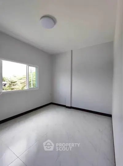 Bright empty room with large window and white tiled floor
