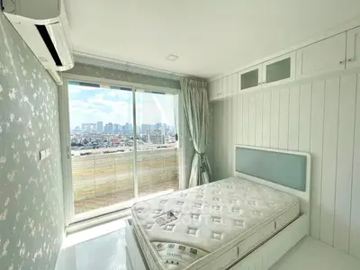 Bright bedroom with city view, featuring large windows and modern decor.