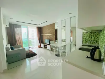 Modern open-plan living room with kitchen, featuring sleek design and ample natural light.