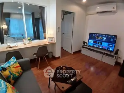 Cozy living room with modern decor, featuring a wall-mounted TV and stylish furniture.